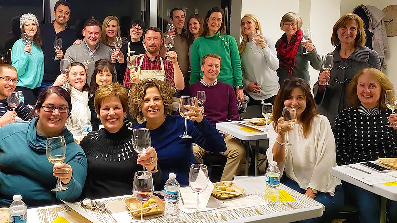 cheese-class-group-toast-full-frame A cheese class raises their wine glasses around the tasting tables.